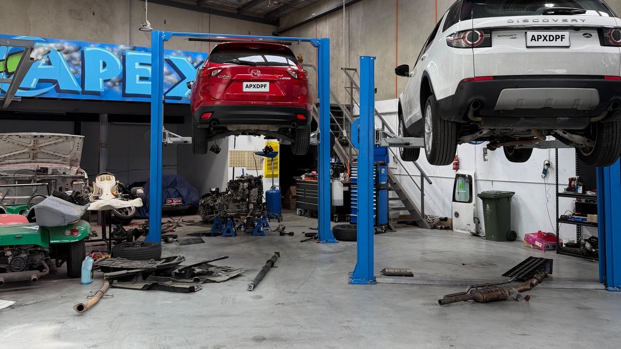 Inside the Apex workshop: two vehicles raised on hoists with removed exhaust and DPF sections laid out on the floor.
